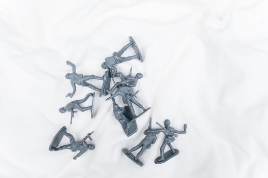 Top view of scattered plastic toy soldiers on a white surface.