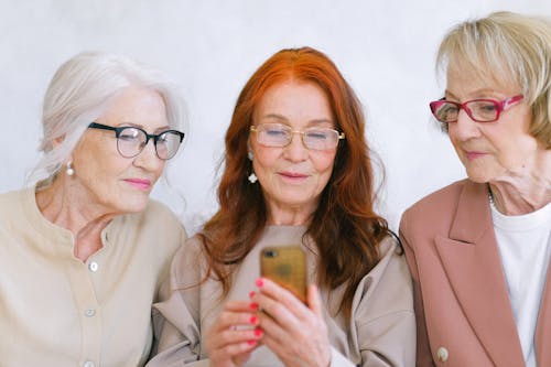 Free Group of elderly fashionable elegant women surfing internet on mobile phone together Stock Photo