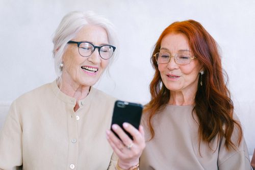 Free Happy senior women looking at screen of mobile phone while watching video through internet Stock Photo