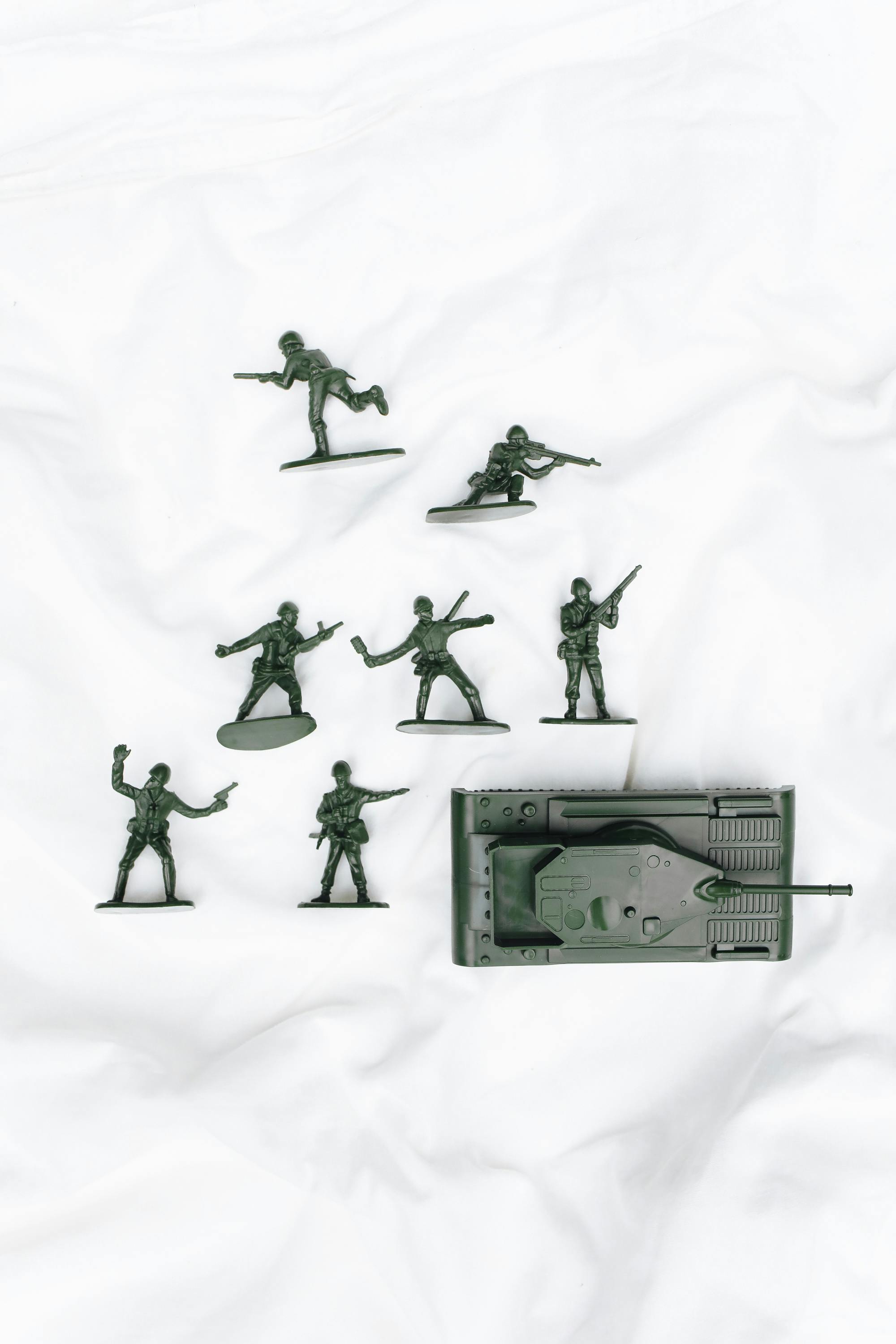 Overhead view of green toy soldiers and tank on a white background, perfect for playtime themes.