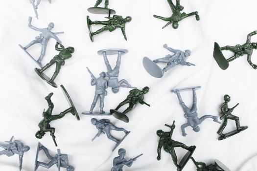 Green and grey plastic toy soldiers arranged randomly on a white background.