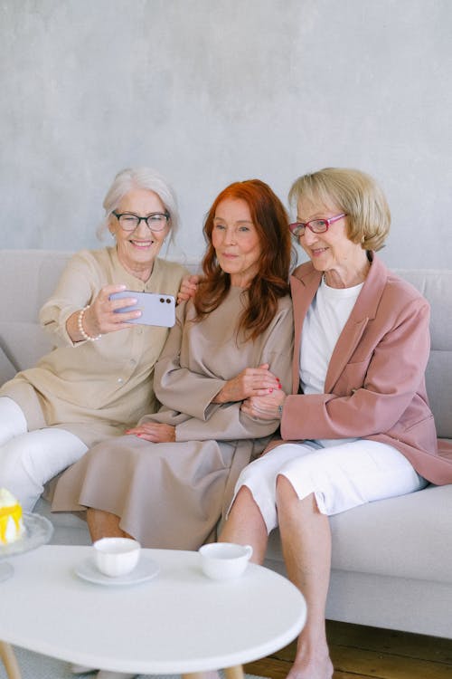 Aged women taking selfie with smartphone at table with cups