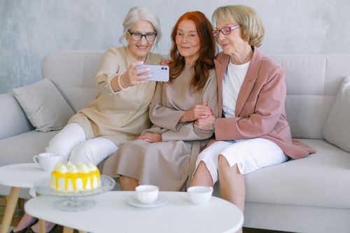 Free Happy senior women taking selfie on mobile phone at table with sweet delicious cake and cups Stock Photo