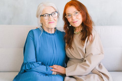 Happy aged women in eyeglasses holding hands