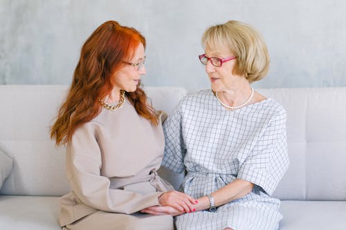 Aged women holding hands and talking on sofa