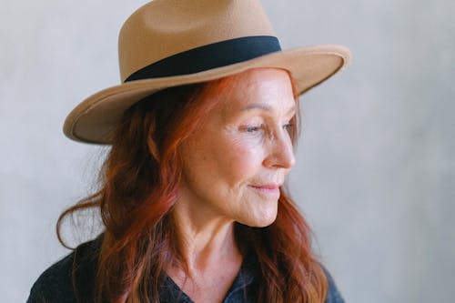 Senior woman with wrinkles and red hair in hat