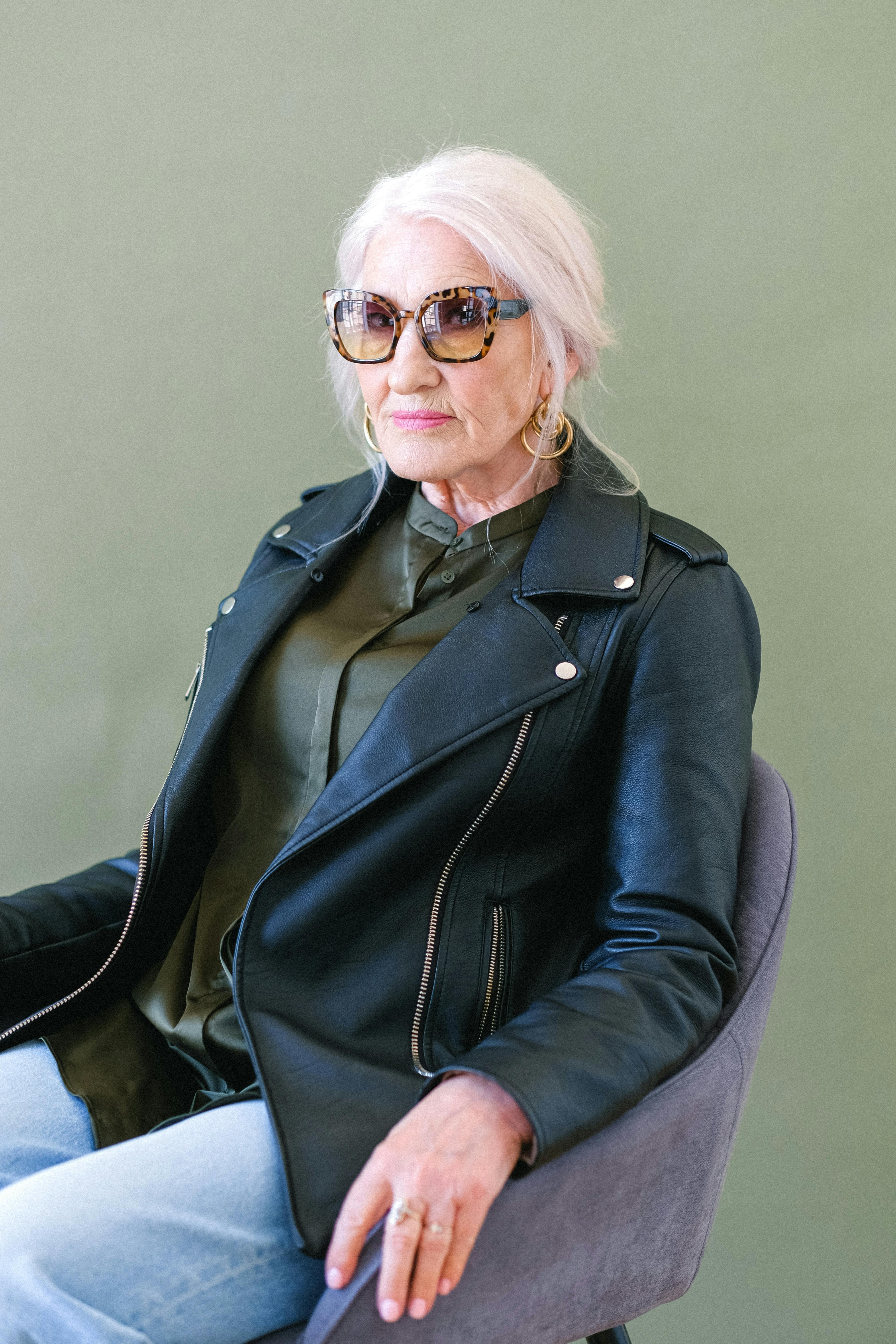 senior woman in fashionable sunglasses and jacket in armchair