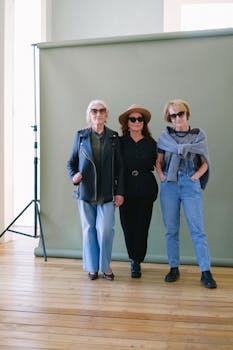 Three stylish senior women confidently pose indoors wearing sunglasses and chic outfits.