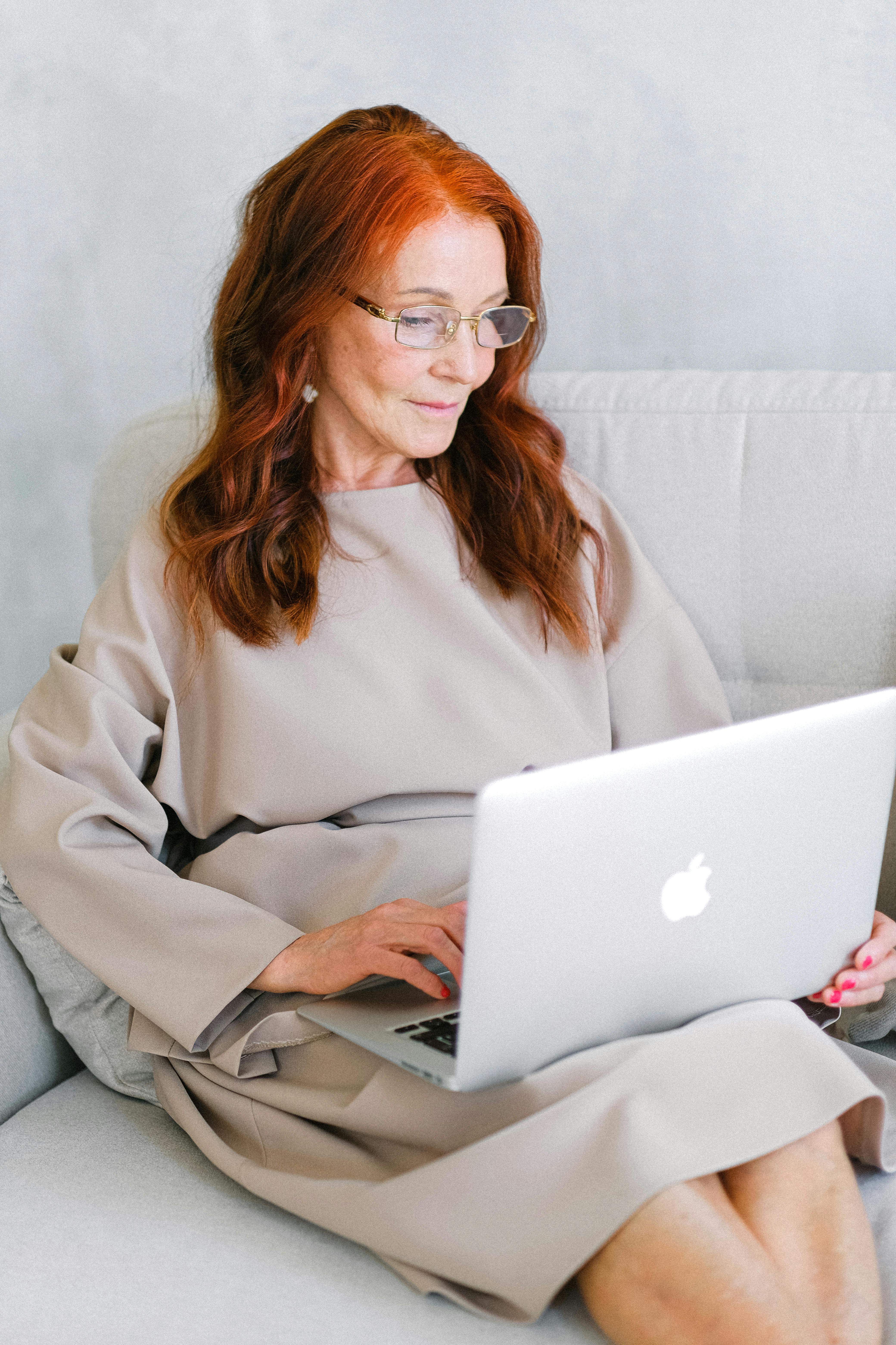 aged businesswoman in eyeglasses typing important report on laptop