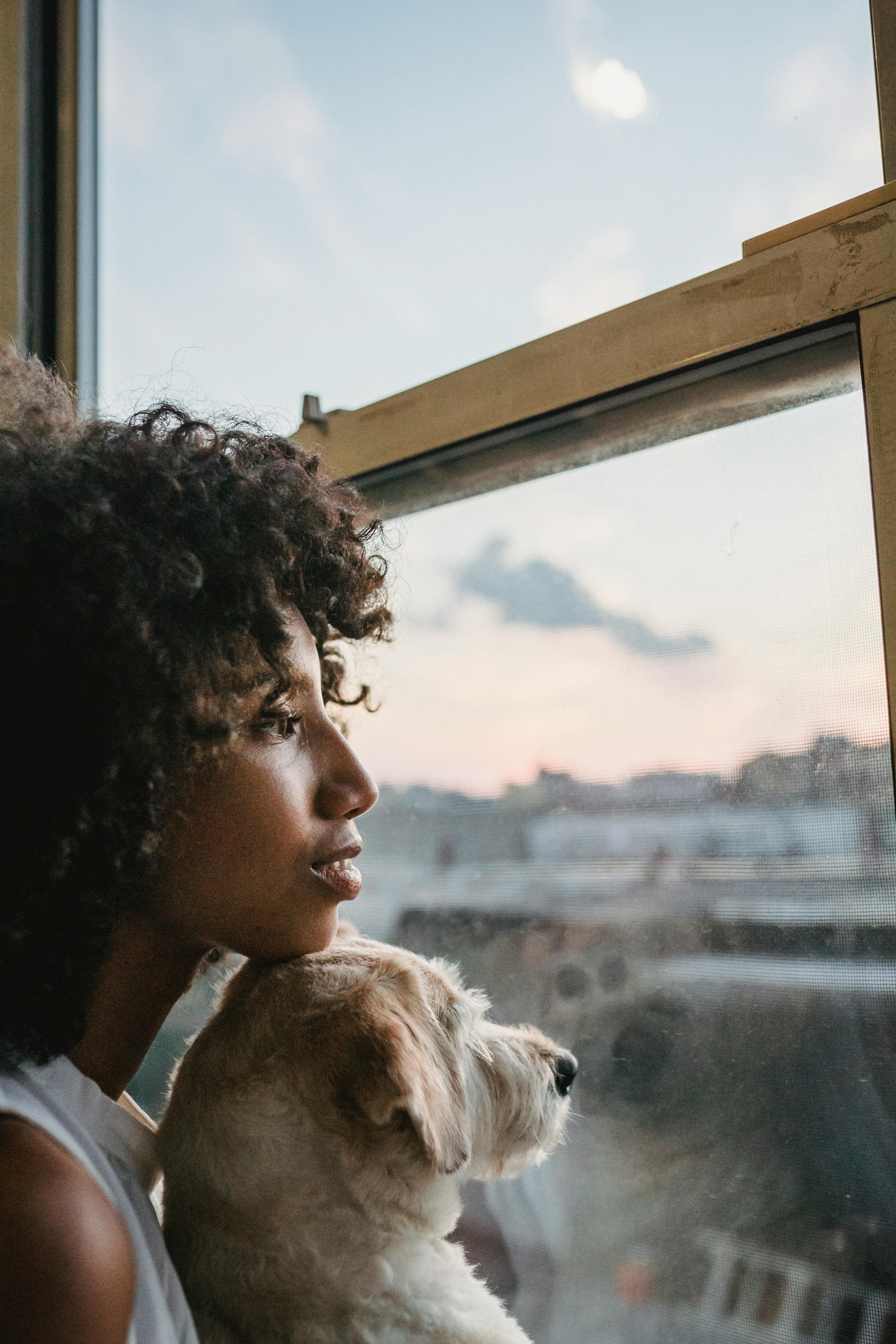 woman in black shirt looking at the window with her dog