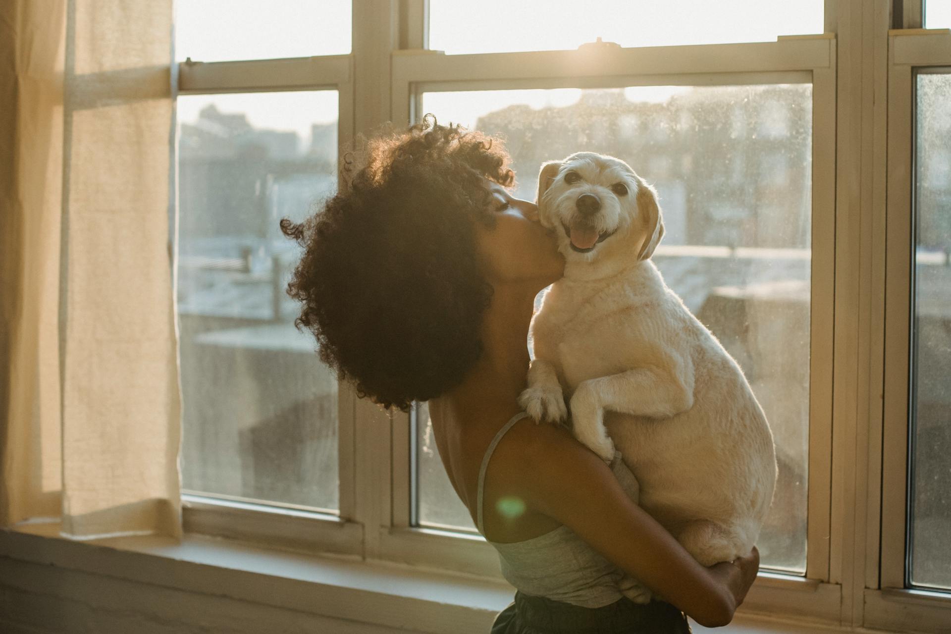 Une femme noire embrassant un mignon chien de race .