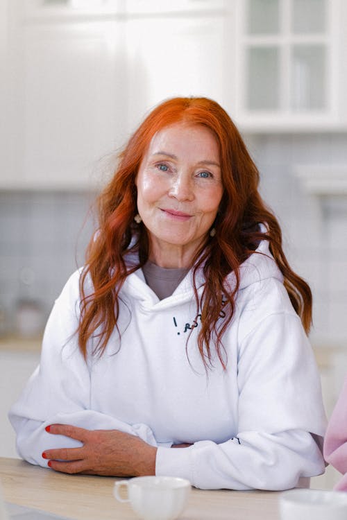 Cheerful senior woman sitting at table with cup of tea