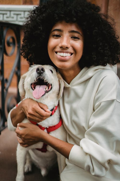 Happy black woman cuddling dog on street