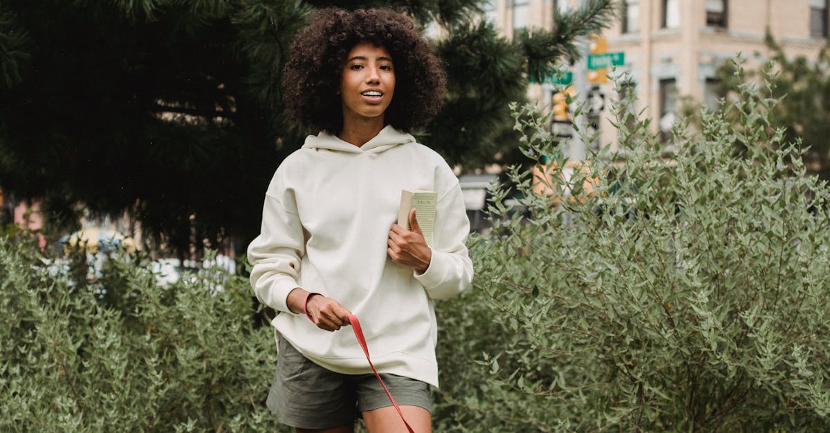 Happy young black lady with obedient dog standing on grassy lawn in park