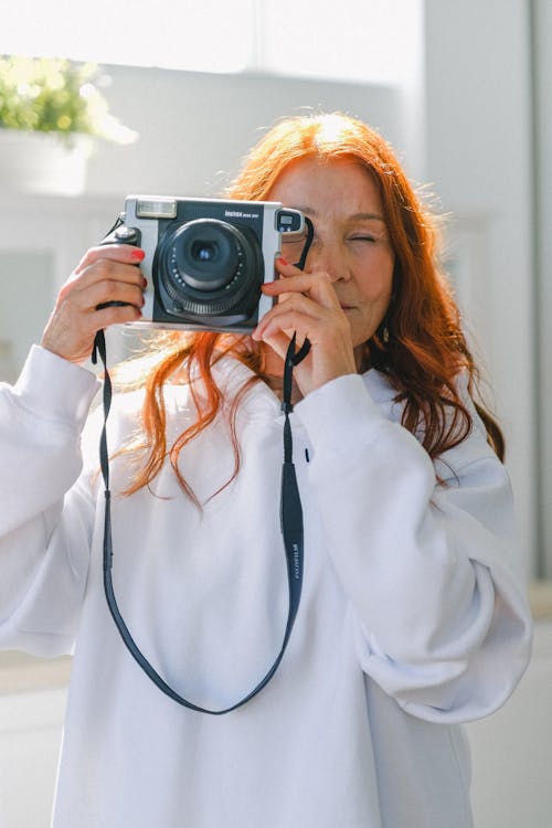 Senior red haired woman with vintage camera