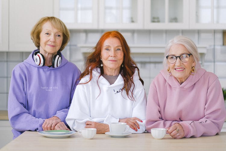 Happy Elderly Women Sitting At Table With Coffee