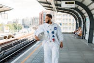 一名身着宇航服的男子在城市火车站手持头盔，将太空主题与城市生活融为一体