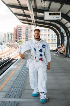 一名穿着宇航员服装的男子自信地站在伦敦火车站