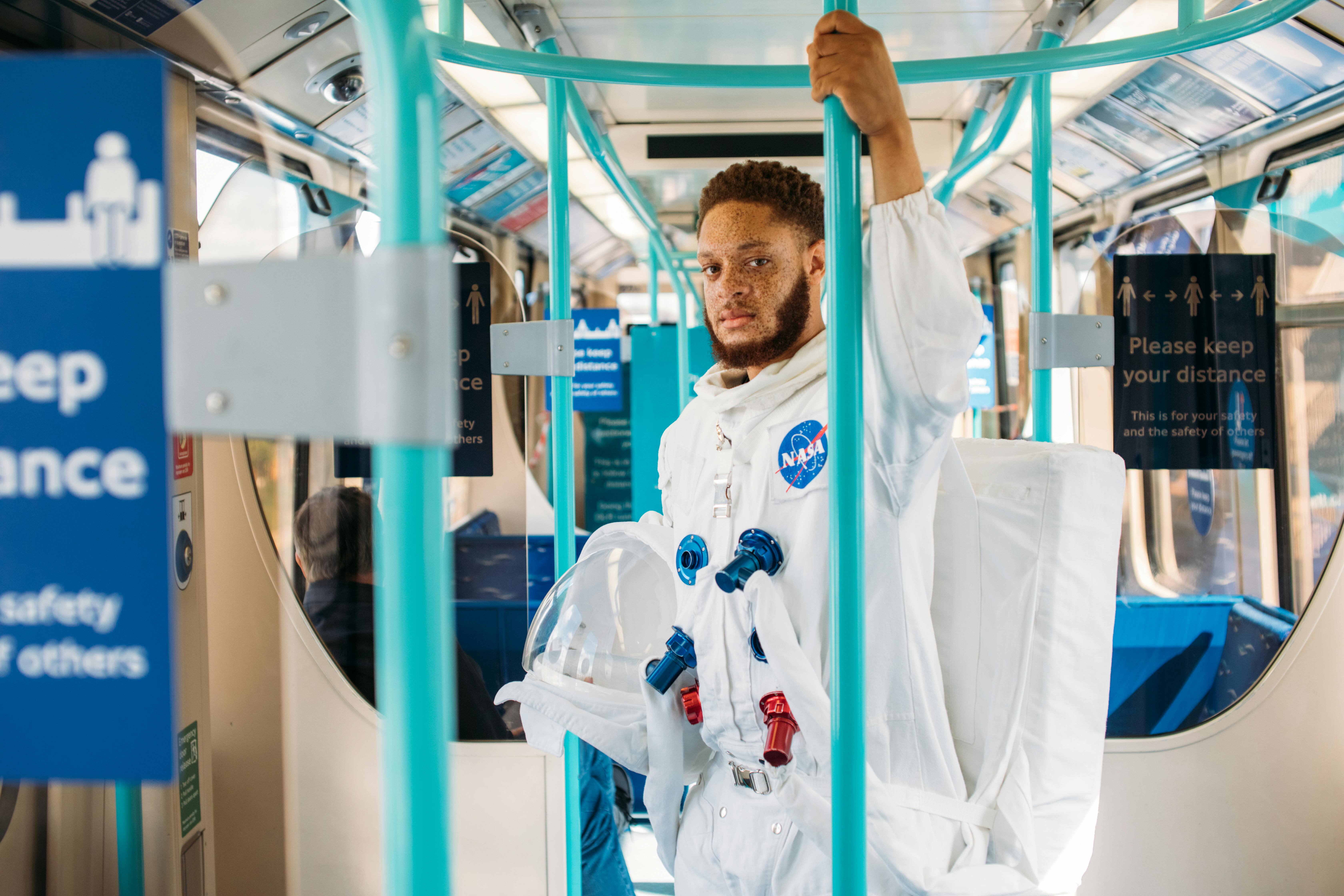 Man in astronaut suit on London subway, blending space exploration with urban life.