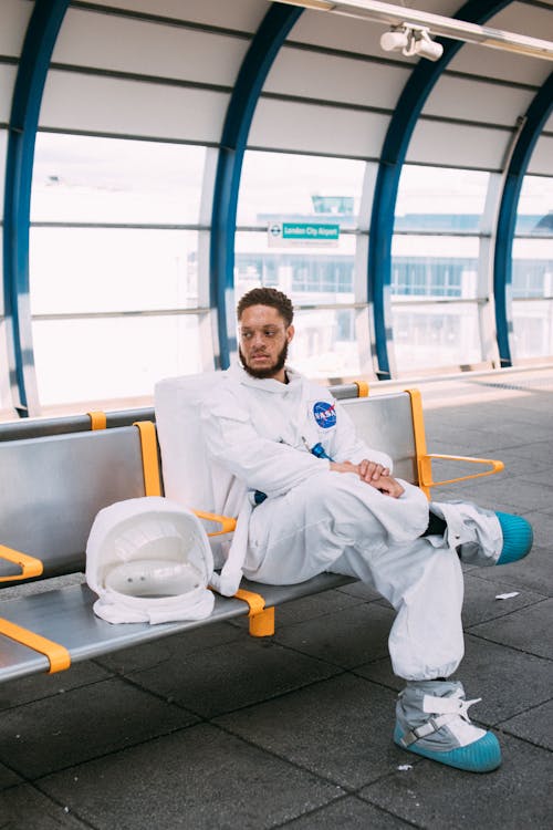 Free Man In An Astronaut Costume Sitting On A Bench Stock Photo