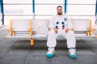 一名穿着宇航员服的人坐在现代中转站的长凳上