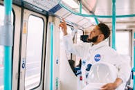 一名穿着太空服的非裔美国人正在伦敦的火车上查看头顶的信息