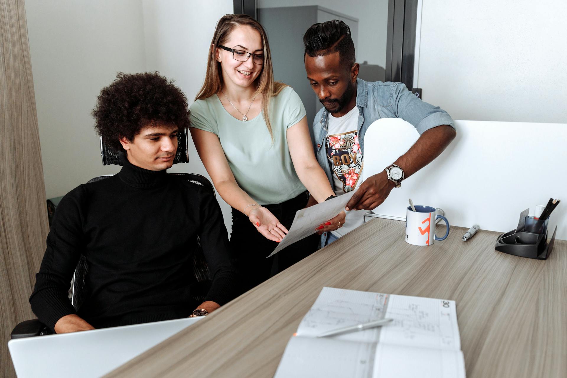 A diverse group of young professionals collaborate over documents in a modern office.