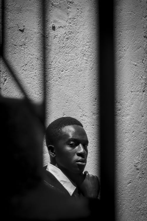 Grayscale Photo of Man Standing Near a Wall