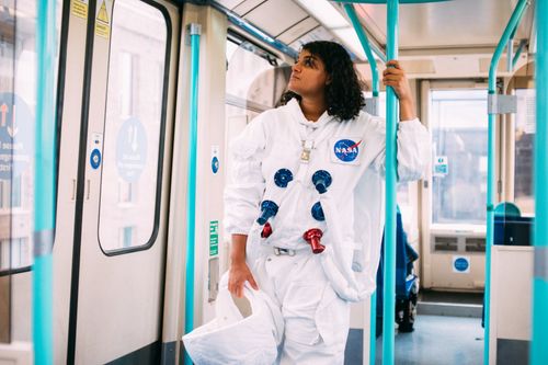 Free A person in an astronaut suit riding a train, blending sci-fi with everyday life. Stock Photo