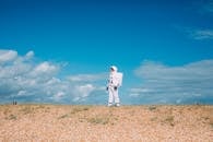 一个宇航员穿着宇航服，独自站在明亮的蓝天下的沙漠景观中