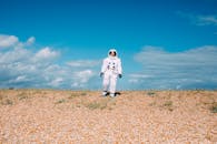 在明亮的天空下，宇航员穿着户外服装走在鹅卵石景观上