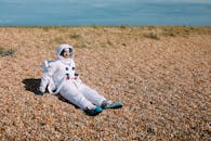 晴朗的天空下，一个穿着太空服的人坐在岩石地形上，唤起了有趣的太空探索主题