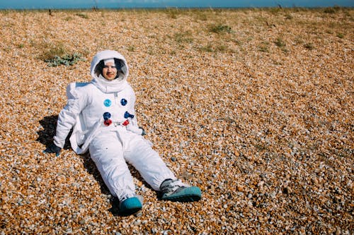 Person Wearing A Space Suit Sitting On A Field