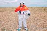 一名男子身穿太空服，手持头盔和红旗，站在岩石地形上