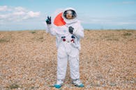 一个穿着太空服的人在户外举着旗帜，比出和平手势