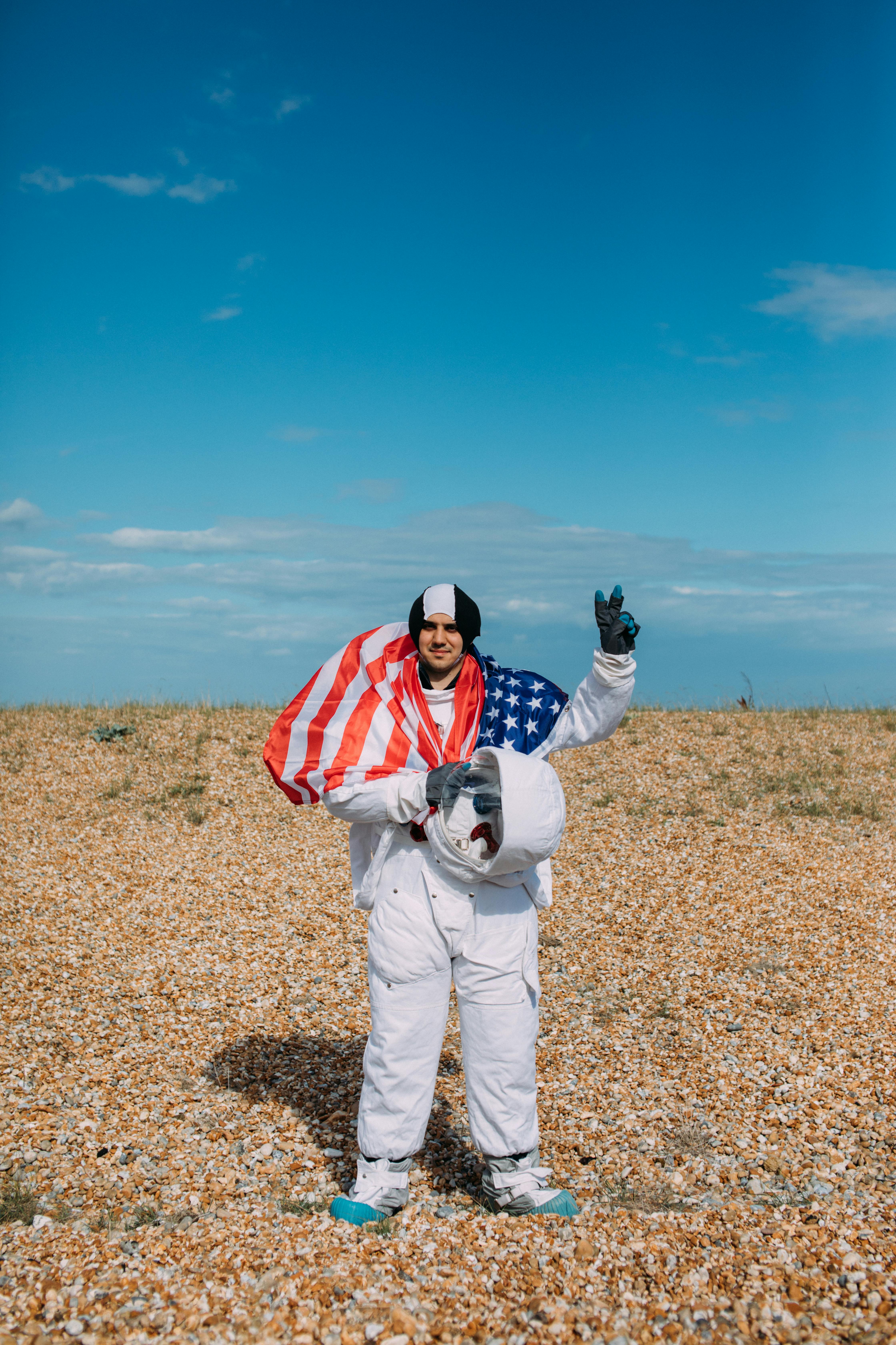 白天，宇航员穿着美国国旗在岩石地形上