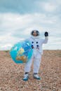 宇航员穿着服装，在圆石滩上与地球仪一起挥舞着问候