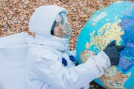 身穿太空服的宇航员指着地球仪，描绘了一个探索概念