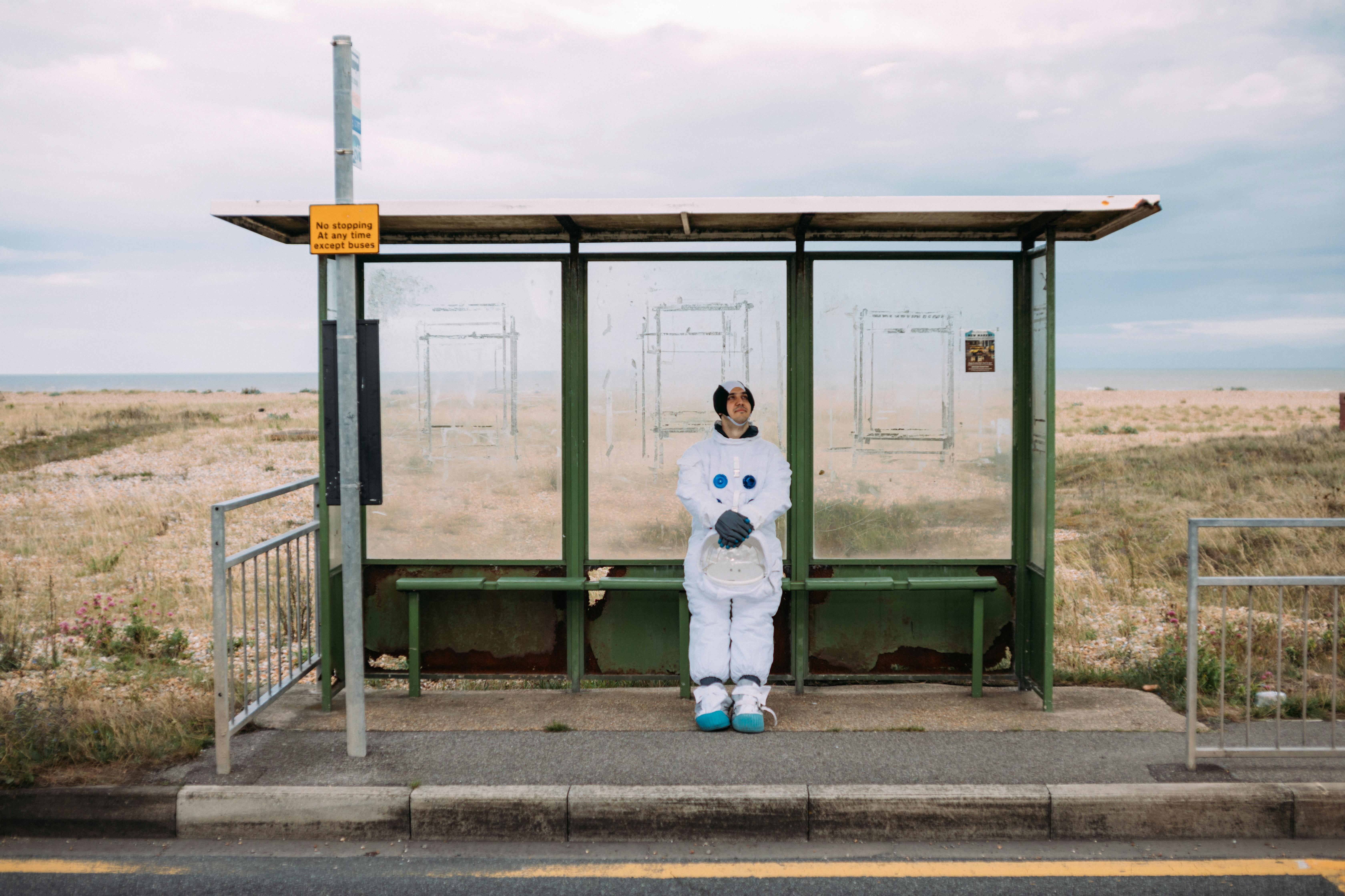 Person In A Space Suit Waiting At The Bus Stop · Free Stock Photo