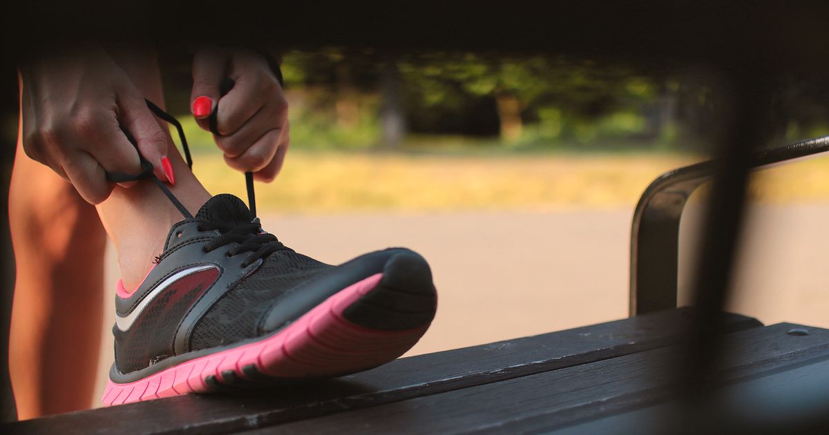 Woman tying her trainers on a park bench, ready to start again