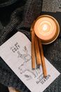 这幅构图温暖而诱人，包含了蜡烛、肉桂棒和舒适的节日贺卡