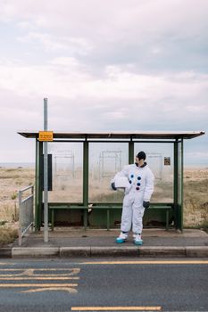 一名穿着宇航服的人正在乡村的公交车站等候