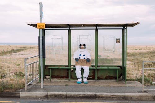 Astronaut Wartet An Einer Bushaltestelle