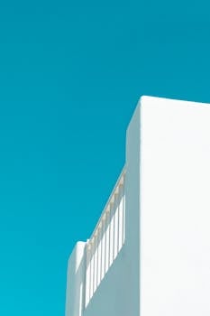 A minimalist shot of a white building with a vibrant teal sky in Mykonos, Greece.