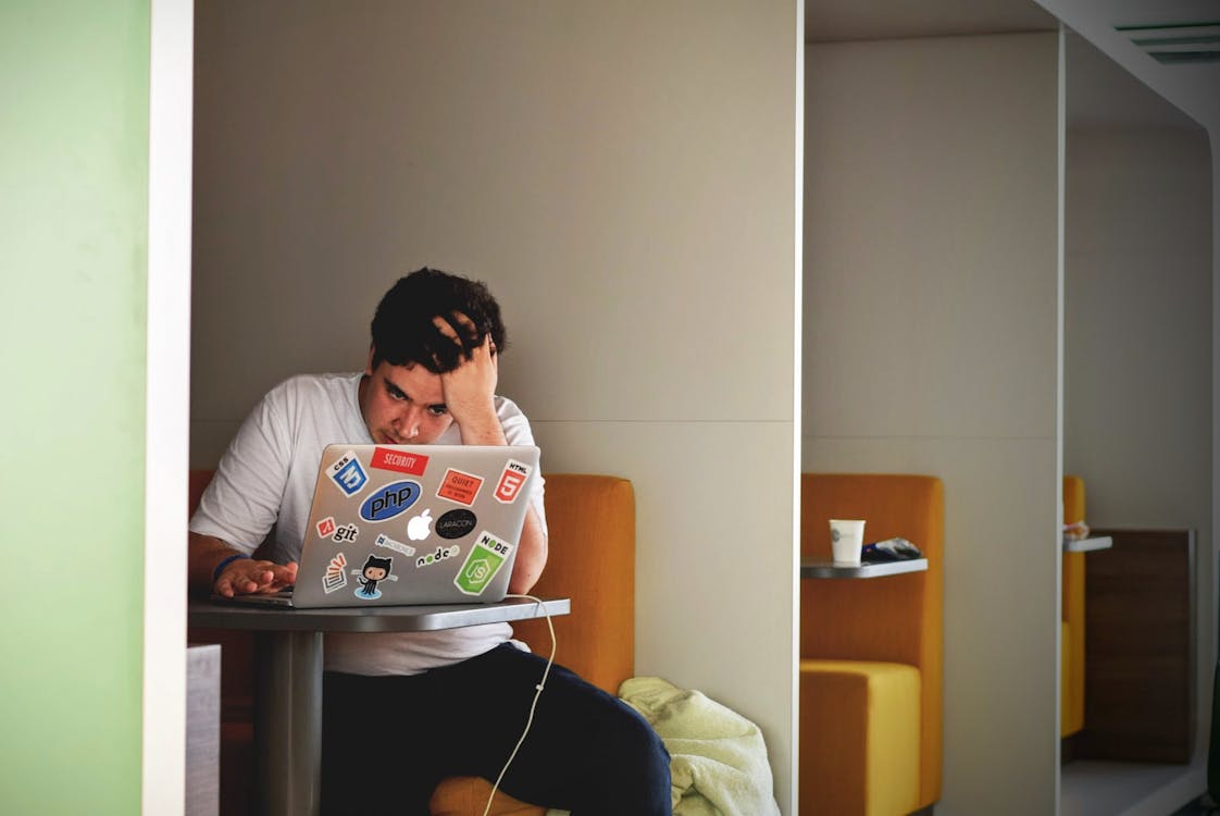 Man in White Shirt Using Macbook Pro feeling the effects of stress (eg. headeache)