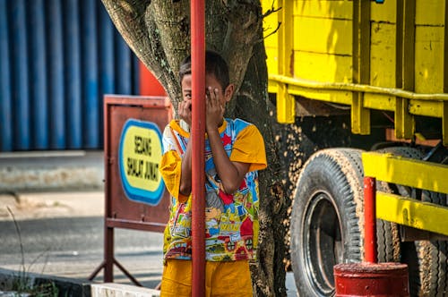 Free Boy in Yellow T-shirt Hiding Behind a Post Stock Photo