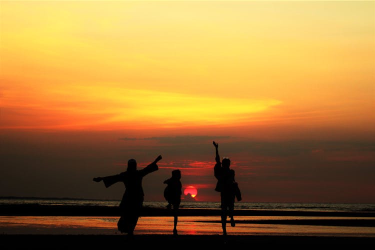 Silhouette Of People Running At The Beach