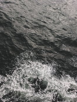 高角度的黑白镜头捕捉了海浪撞击的瞬间，展现了大海的戏剧性运动