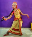 一名女子身着传统印度舞蹈服装，在室内摆出古典姿势