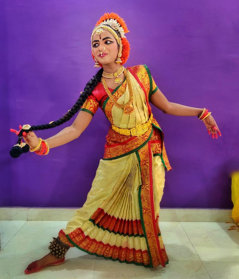 Woman in traditional Indian dance costume performing a classical pose indoors
